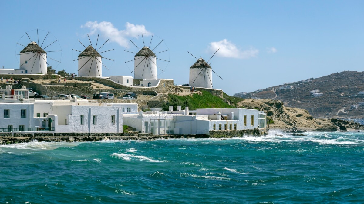 a row of windmills sitting on top of a hill next to the ocean
